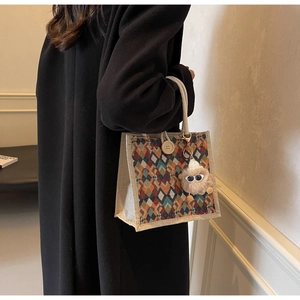 Detail of colorful geometric jacquard handbag with woven handles and plush charm