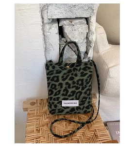 Detail view of green leopard print canvas mini bag with bronze snap and logo label