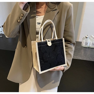 Detail of hand-woven beige handle and black rose embossed floral pattern on small tote bag