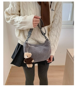 Détail d'un sac bandoulière gris en peluche avec un petit ours et une sangle réglable