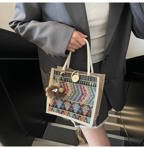 Detailed embroidery on a beige canvas tote with a cute plush monster charm detail