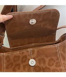 Detailed macro view of silver magnetic snap closure on leopard print suede bucket bag