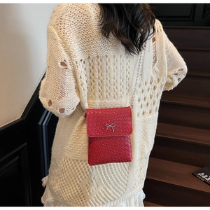 Macro detail of red woven texture mini bag with silver bow accent and metal chain