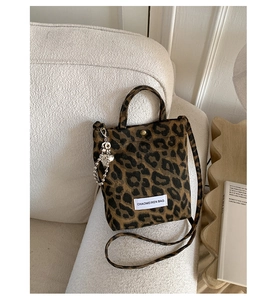 Detail view of leopard print crossbody bag with heart charm on a textured background