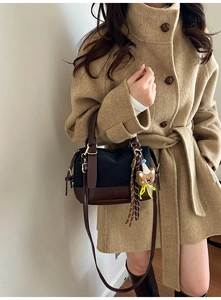 Detail einer Retro-Umhängetasche aus schwarzem Canvas und Leder mit Bären-Anhänger