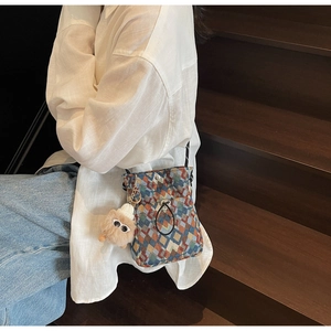 Détail du sac bandoulière tricoté coloré avec motifs géométriques et pompon peluche
