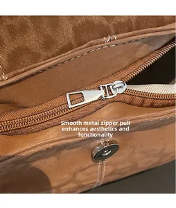 Detailed view of brown suede bucket bag with smooth silver zipper and textile lining