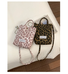 Detail view of two leopard print crossbody bags in pink and brown with snap buttons