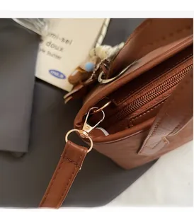 Macro view of golden hardware and lobster clasp on brown leather tote bag