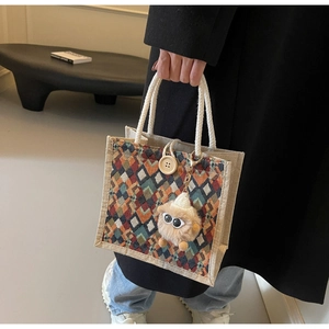 Detail of colorful geometric woven linen tote with rope handle and wooden button