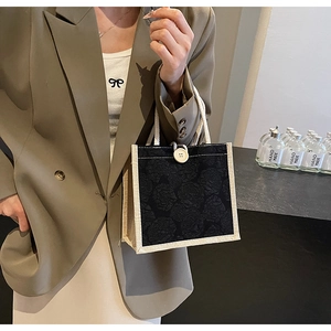 Detail of black rose jacquard tote bag with canvas trim and woven rope handles