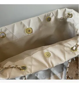 Detail of quilted white tote bag with gold magnetic buckle and metal chain strap