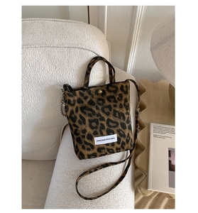 Close-up of leopard print mini tote bag with metal snap button and decorative chain detail