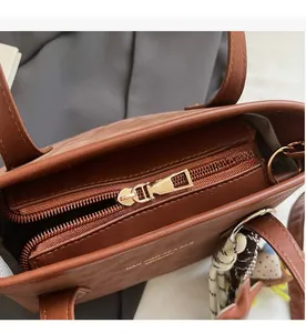 Macro view of smooth gold zipper closure and interior lining on brown leather tote bag