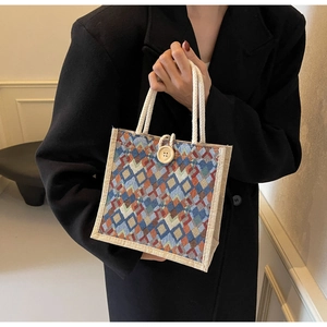 Close-up of geometric jacquard handbag featuring a round wooden button and cotton rope handle