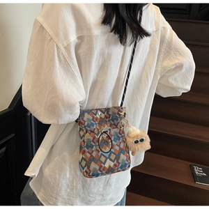 Détail d'un sac bandoulière bohème tissé avec motifs colorés et breloque peluche