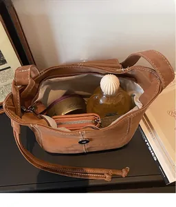 Macro view of brown suede bucket bag with white contrast stitching and spacious interior