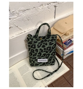 Close-up of leopard print canvas bag with brand label and metallic hardware detail