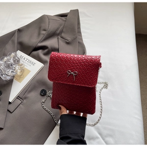 Macro detail of red woven leather mini bag featuring a silver metal bow accent