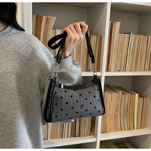 Detail of grey polka dot fabric underarm bag with black leather trim and metal zipper