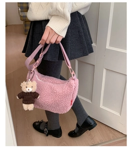 Détail d'un sac bandoulière rose en peluche avec un porte-clés ourson marron mignon