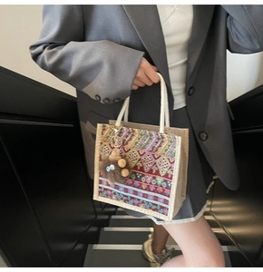 Ethnic patterned tote bag with woven handles and monster charm shown on a model