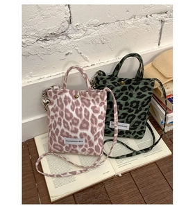 Detail of trendy leopard print mini crossbody bags with silver heart charm and handles