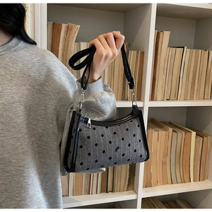 Detail shot of grey polka dot underarm bag with black bow and leather straps