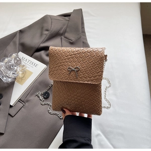 Detail of brown woven faux leather crossbody bag with silver bow buckle and chain strap