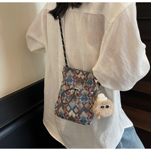 Détail d'un sac bandoulière tissé géométrique avec bandoulière noire et breloque petit monstre