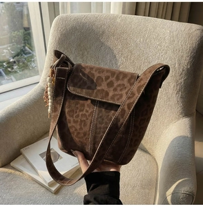 Detail of leopard print suede bucket bag with wooden bead charm and wide shoulder strap