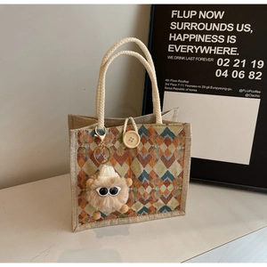 Detail of woven tote bag with geometric waves, wooden button and cute monster charm