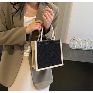 Detail of a mini tote bag featuring black rose jacquard fabric and woven handles