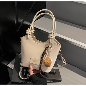 Detail of cream bucket bag with unique ring handles on a design book background
