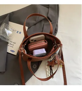 Top view of large brown leather tote bag interior showing phone, wallet, and star pendant