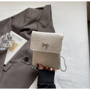 Detailed macro view of white woven texture PU leather bag with silver bow and chain