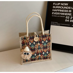 Detail of woven tote bag with colorful geometric patterns and monster charm