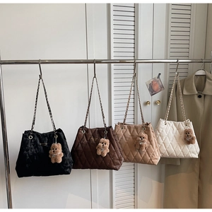 Detailed view of quilted tote bags in four colors hanging on a metal rack display