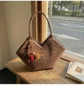 Detail view of large leopard print suede tote bag with decorative pompom keychain