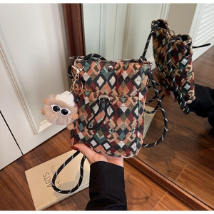 Detail of colorful geometric woven crossbody bag with plush charm and snap closure