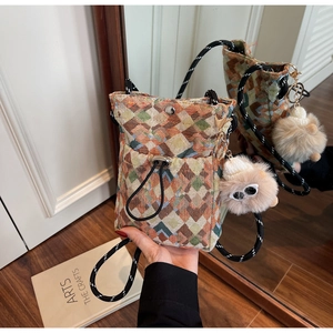 Détail du sac à téléphone tissé bohème avec motif jacquard et pendentif peluche