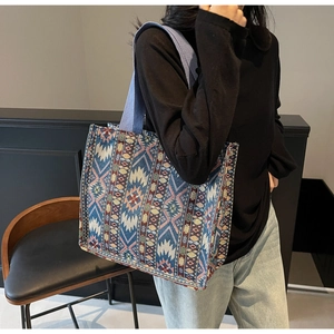 Detail of large woven tote bag with ethnic geometric patterns and blue shoulder straps