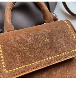 Macro detail of brown pebble leather handbag featuring yellow stitching and gold logo