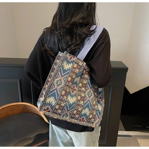 Detailed embroidery and wide purple shoulder strap of this ethnic tapestry tote bag