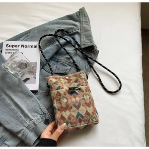 Détail de la pochette téléphone tissée avec motif à losanges et bandoulière tressée
