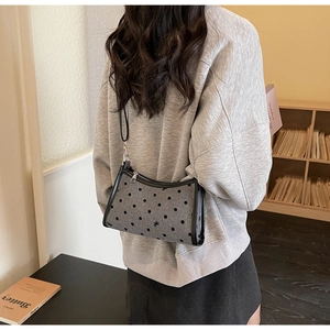 Lifestyle shot showing the polka dot shoulder bag worn in a cozy home setting