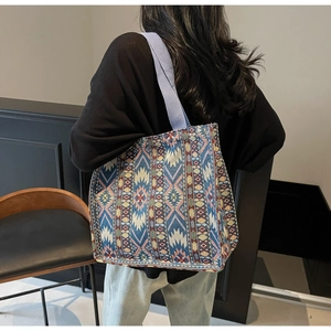 Detail view of ethnic woven tote bag featuring geometric patterns and blue shoulder strap