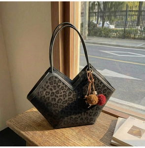 Detail of leopard print tote bag with V-shaped opening and plush pom-pom charm