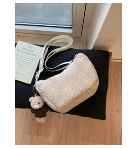 Détail de la texture d'un sac bandoulière en peluche beige avec charm ours mignon