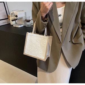 Detail of white jacquard relief fabric with jute side panels and rope handle